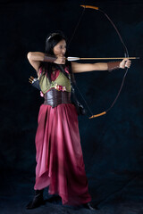 An elf warrior queen wearing a laced bodice and draped skirt and holding a bow and arrow