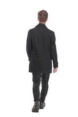 Back view of going handsome young business man in coat walking away.