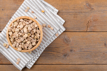 Dry raw cicerchia or indian pea on a wooden bowl with napkin on natural wooden background, top...