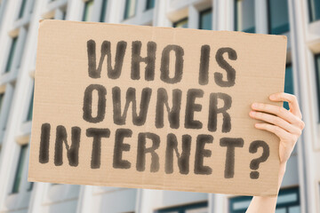 The question " Who is owner Internet? " on a banner in men's hand with blurred background. Employment. Network. Technology. Connection. World. Lan. Wires. Control. Security