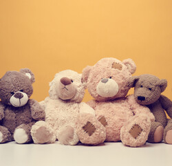 group of cute brown teddy bears sit on yellow background, childrens toy