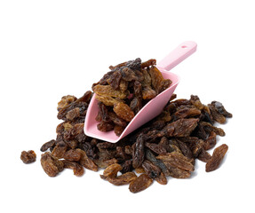 a bunch of dried brown raisins in a plastic pink spoon on a white background