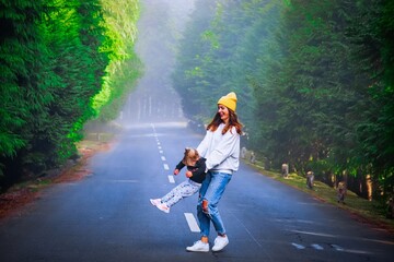 mother with her child is playing in the forest 