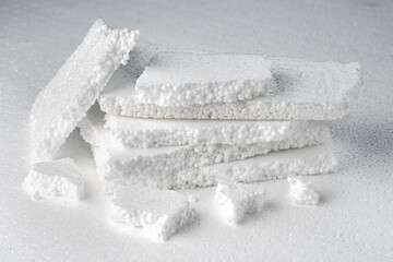 Stack of broken pieces of white styrofoam on the sheet of white styrofoam
