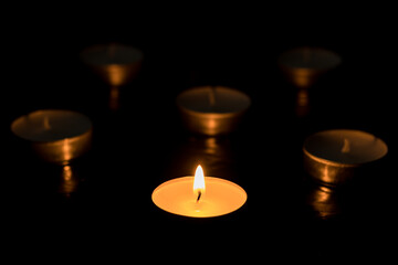 One candles Burning out of six on dark table, black background, Memory day.