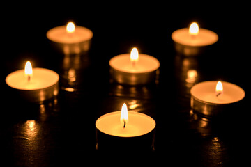Obraz na płótnie Canvas Burning candles on dark table, black background, Memory day.