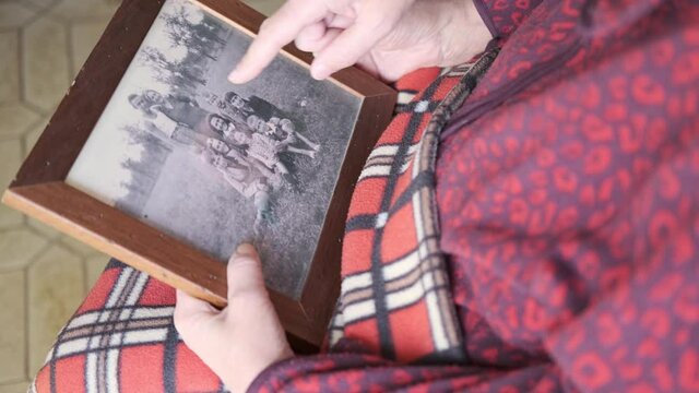 An elderly woman with a photo frame in her hand. The senior woman holds a frame in her shivering hands recalls memories. 
