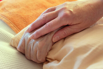 Insights into the home care of relatives in one's own family with dementia. etc. Hands of a dementia patient are held.