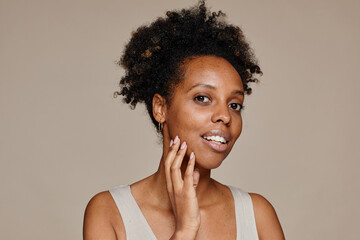Minimal portrait of young African-American woman looking at camera while posing against neutral...