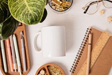 Modern eco friendly desktop with zero waste stationary and white mug mockup. Comfortable working space, sustainable life style concept. Top view, flat lay.