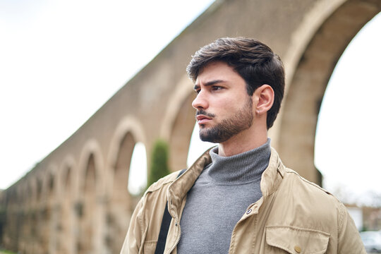 Thoughtful bearded man standing against arched wall