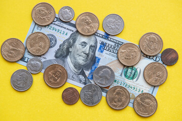 US dollar bills and coins. one hundred dollar bill and coins of different denominations around on a yellow background
