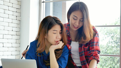 Happiness two women working together confident team meeting in office desk. Team business partners working with computer laptop startup company. Asian colleague friendship at work with smiling face.