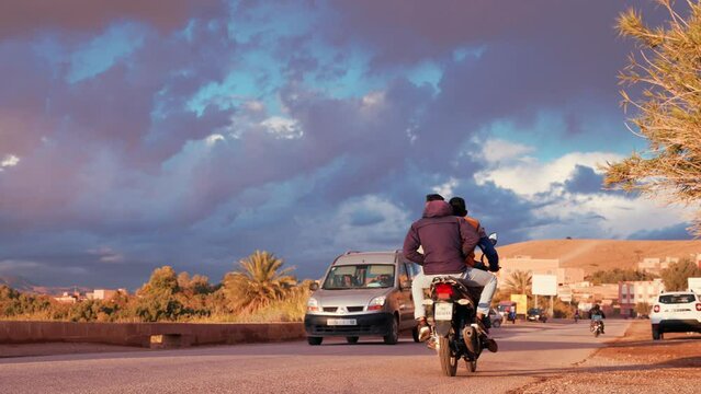 Scenic view of traffic - cars and motorcycles moving down road against mountain landscape. Road trip through Morocco.