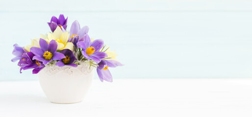 Bouquet of spring flowers in a vase. Snowdrop or lumbago on a light background with copy space
