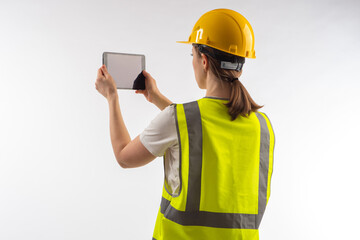builder photographs something on tablet. Woman builder with electronic tablet. Concept - she makes photo report on work done. Builder with tablet on white background. Architect in working uniform.