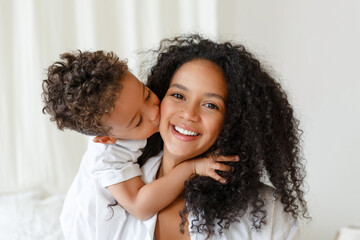 Loving young african American mother hugging cute baby, son.  Smiling mom playing with little child toddler at home. Childcare concept. Woman and kid enjoy family time together