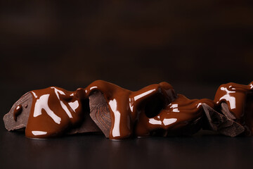 molten chocolate flows over broken pieces on black table
