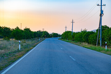 Fototapeta na wymiar at sunset an asphalt road goes towards the mountains