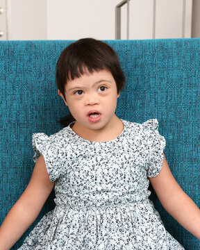Southeast Asian child girl female special need medical down adhd autism syndrome look happy smile emotion expression blue color sofa