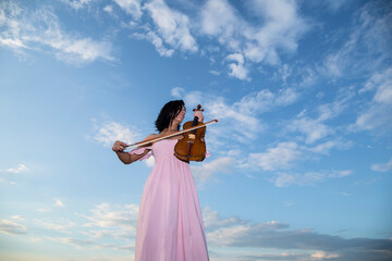 The girl with a violin outdoor. Sky background. Love girl. Sensual. Music
