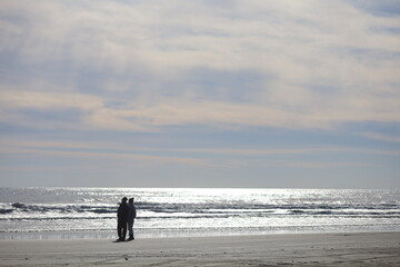 冬の海を見つめる男女のシルエット