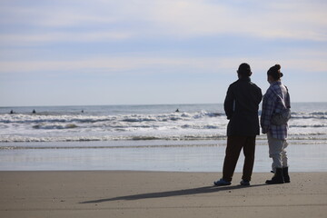 冬の海を見つめる男女のシルエット