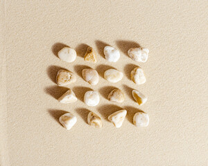 Pattern with white pebble sea stones on fine sand. Square composition from natural stone neutral beige color, monochrome tones. Spa minimal background
