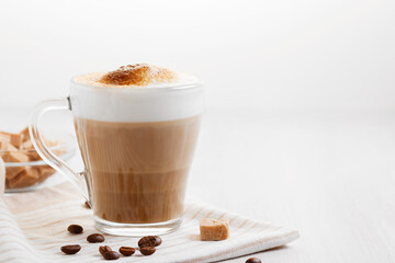 Latte coffee poured in layers with froth and a crispy chocolate top on a light kitchen table, copy space