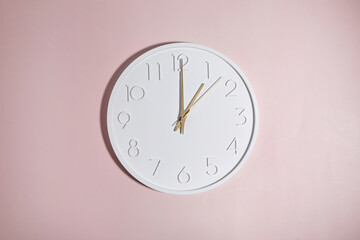 A white circle watch against a pink background.