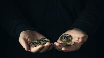 Handful of bitcoins in male palmson a dark background. Financial savings, accumulation in cryptocurrency concept. Selective focus