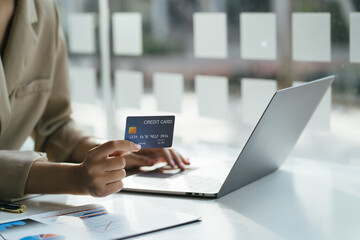 Woman shopping purchasing online, using laptop, checking balance, browsing internet banking service, paying by credit card, making payment.
