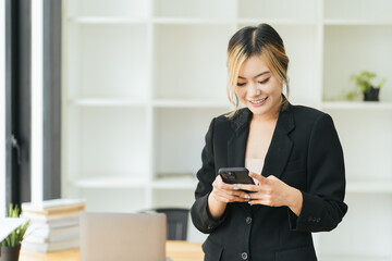 Successful young business woman using a smartphone while standing in front of her own business...