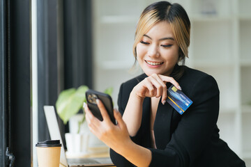 Business people shopping via online application media concept. Happy smile young adult asian woman consumer using creadit card and smartphone.