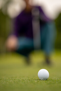 Focus on golf ball with golfer blurred in background