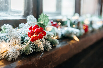 Christmas garland with red berries and snow on the tree, on the window.