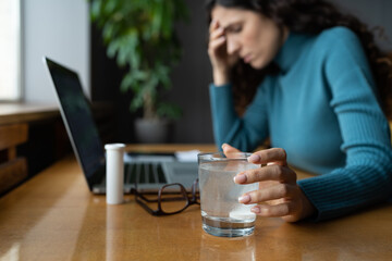 Obraz na płótnie Canvas Unhealthy woman feel unwell suffer from migraine headache, take pill analgetic medication to relieve pain. Stressed lady dissolving tablet in glass of water sitting at office desk, selective focus