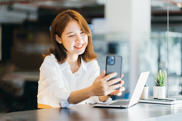 Obraz na płótnie Canvas Hi nice to meet you. Joyful Asian young lady having a video call with a smart phone.