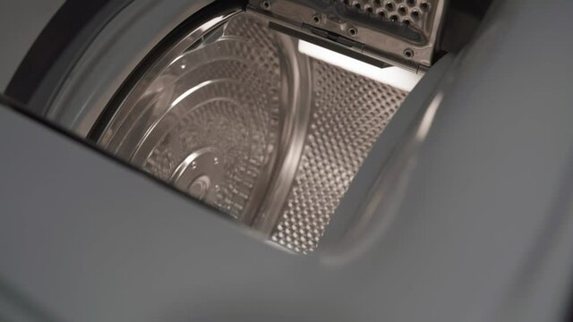 The camera flies into the drum of a top-loading washing machine