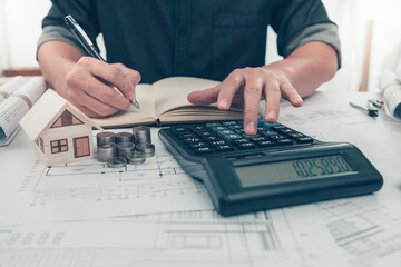 Architect engineer use calculator check cost house design on bueprint. Cost House planning design...