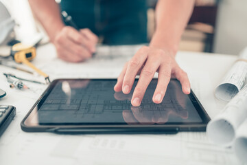 Architect engineer use tablet read and check drawing design working on bueprint. House planning...
