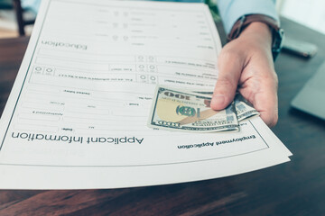 Men attach money to job applications. A man bribe for a new job..job vacancy, job application...