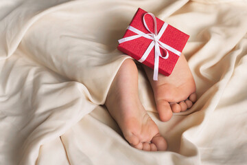 Children's feet and heels on a white bed to Christmas, Valentine's day. Infant baby is sleeping in his crib. Importance of sleep for babies. Sleep mode babies 3 y.o.