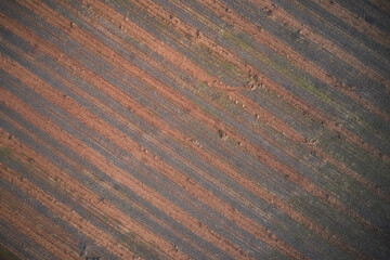 Striped texture brown red color aerial view. Italian arable land in winter season top view. Texture of arable land top view. Winter texture plowed land drone view.