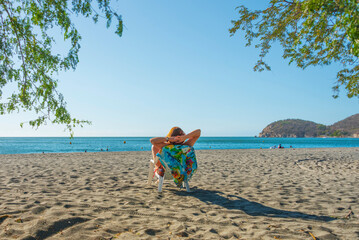 Obraz premium Girl relaxed on a chair looking at the horizon on a beach, on a sunny day. 