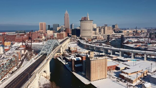 Drone push in shot of downtown Cleveland Ohio skyline on a sunny Winter afternoon with snow covering the landscape