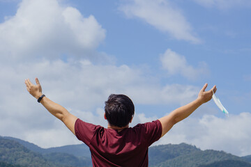 Man taking off mask outdoor.Coronavirus ended.Take off the mask.End of quarantine, covid-19.blue sky background, enjoys life, breathes fresh air after coronavirus pandemic.