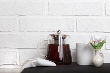 Kitchen cozy light background with copy space in loft style. Glass teapot with tea on the table. Tea break