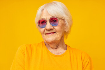 Photo of retired old lady in a yellow t-shirt posing yellow background