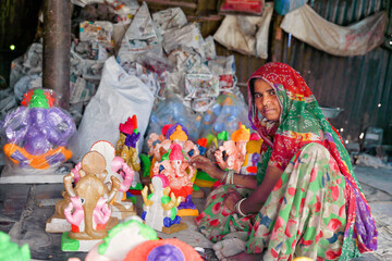 Indian Female worker painting the God Ganapathi statue for festival	
